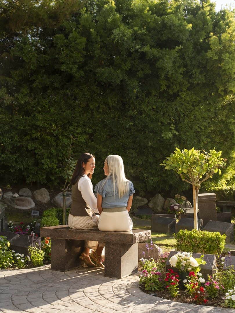 Two women on a bench in a garden setting
